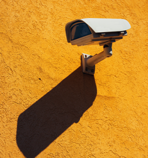 security-camera-on-yellow-wall-P2Z9JCT
